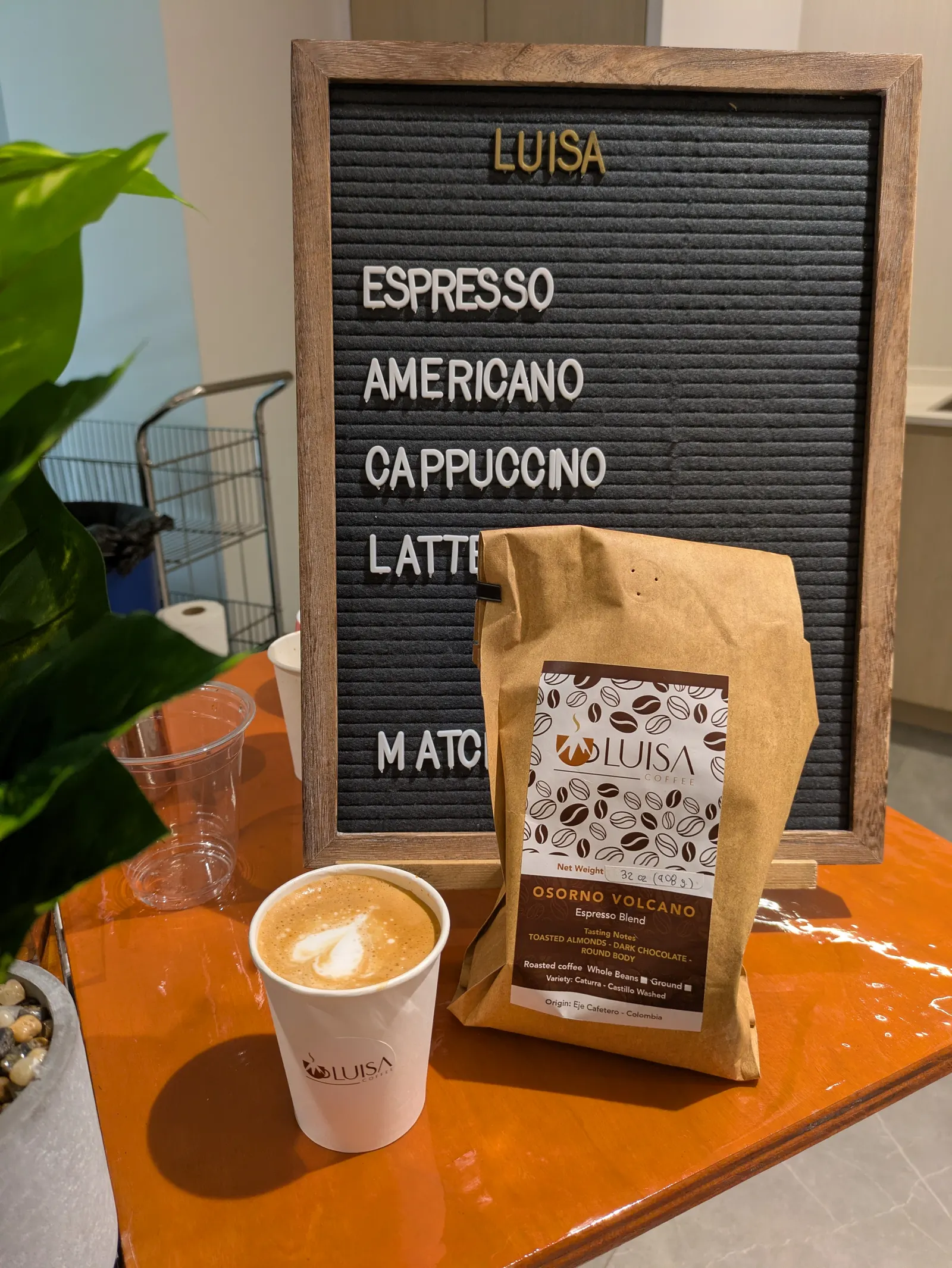 Bag of Luisa Coffee specialty roasted beans with a latte